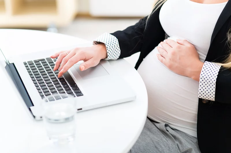 Pregnant woman at work using laptop