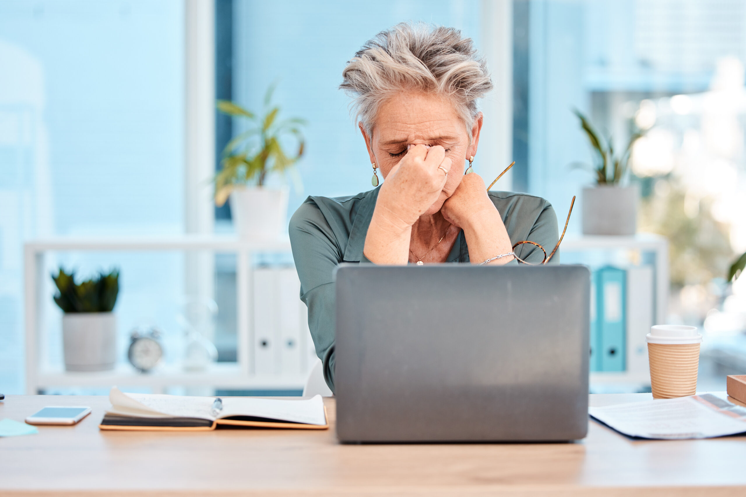 Stress, headache and woman with laptop, mental health and anxiety in office. Depression, business female and entrepreneur with burnout experience, unhappy, overworked and pain for startup company.