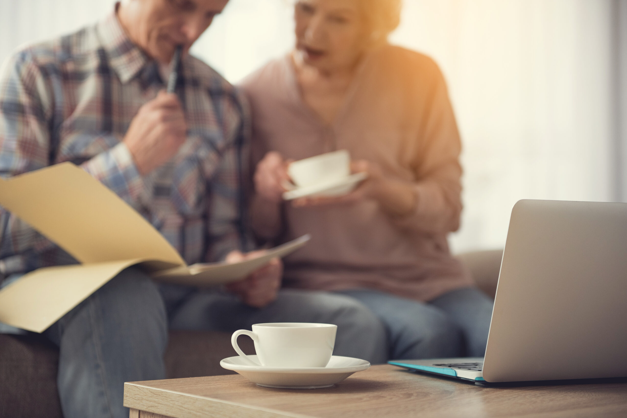 old couple looking over documents with a cup of tea and desk