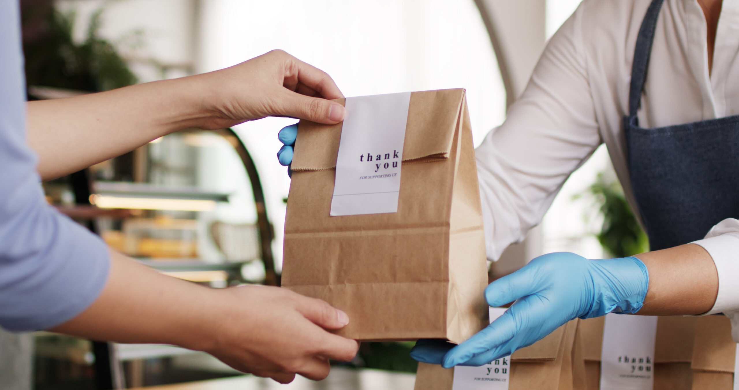 Person handing another person a paper bag which says thank you