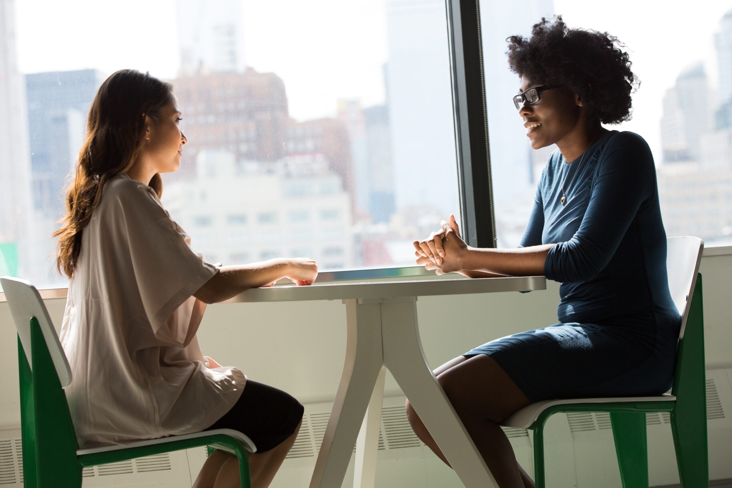 Two people talking at table by window