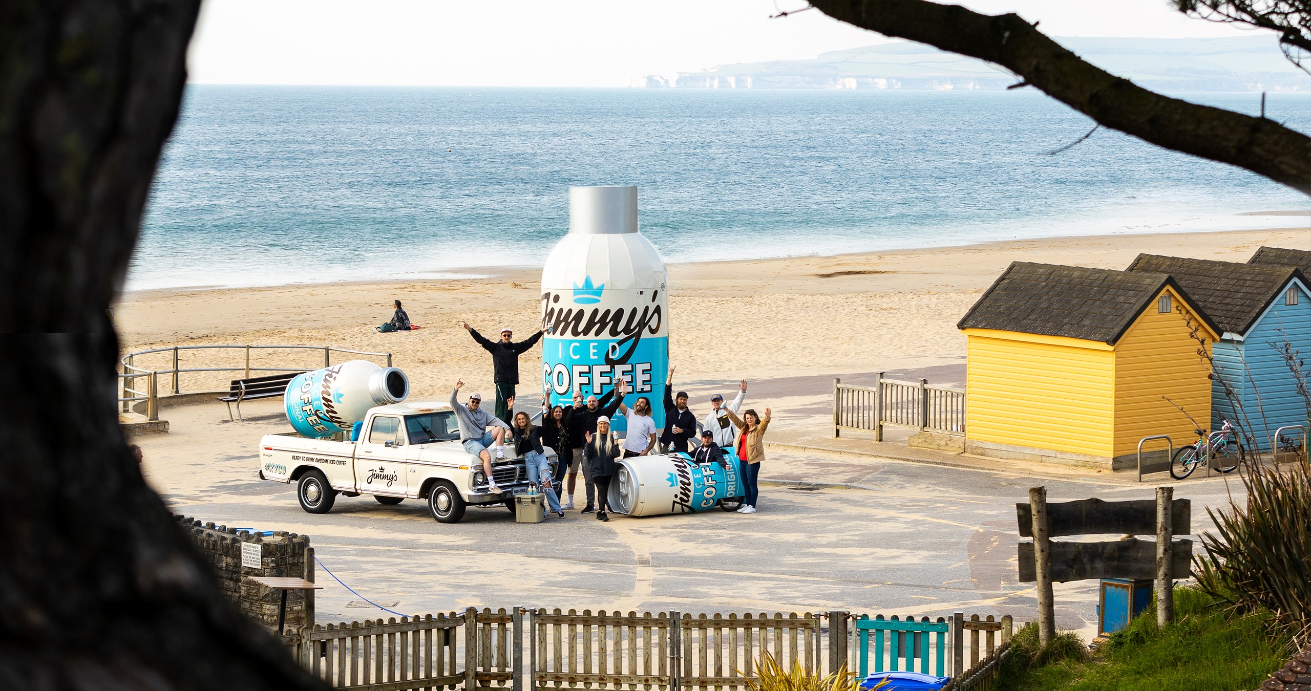 large Jimmy's coffee can on the beach with staff and beach huts and car