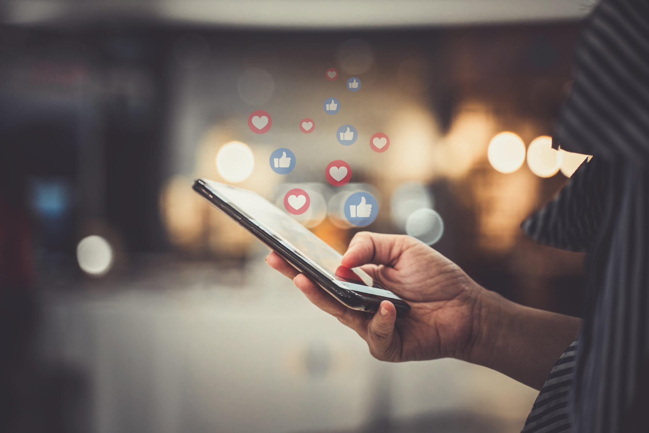 Man holding phone with liked and loved icons from Facebook