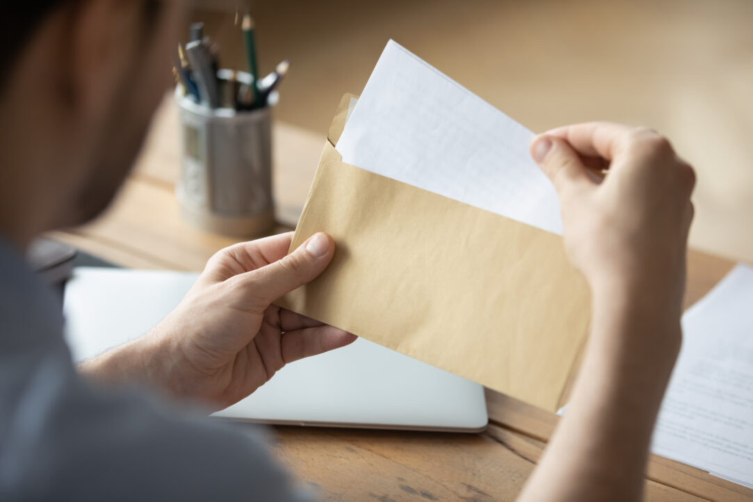 Close up businessman holding envelope with blank paper sheet