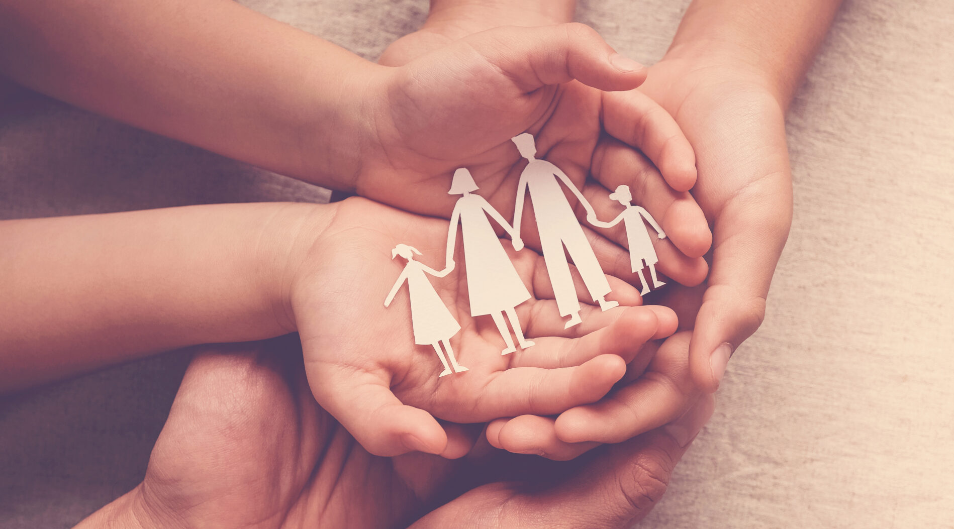 Adult and children hands holding paper family cutout, family home, foster care, homeless support concept