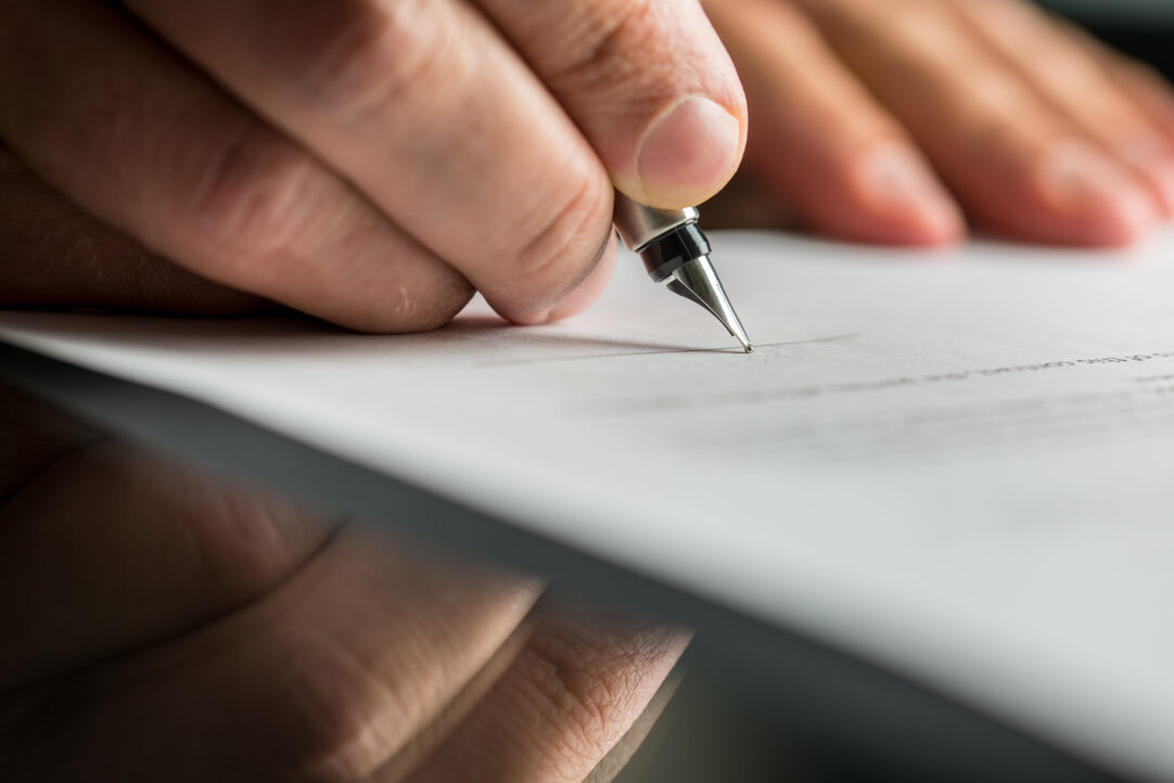 Closeup of male hand about to sign a business contract with a fountain pen.
