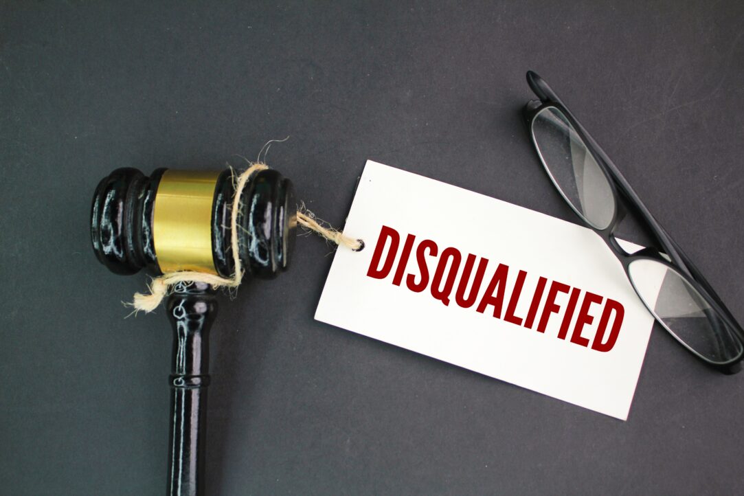 judge's gavel, glasses and a paper tag with the word disqualified. concept of disqualification