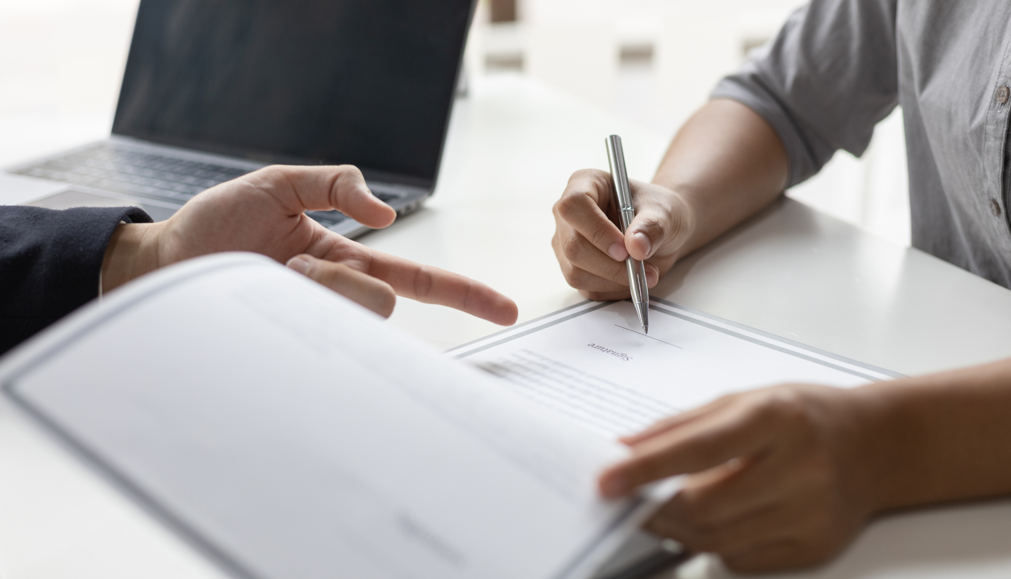 two people looking over document and one signing