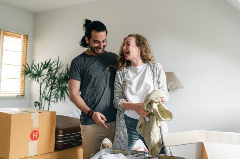 excited couple unpacking boxes in new apartment, moving in together